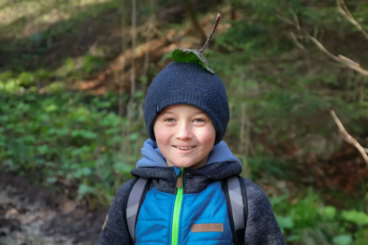 Junge mit Blatt am Kopf im Wald
