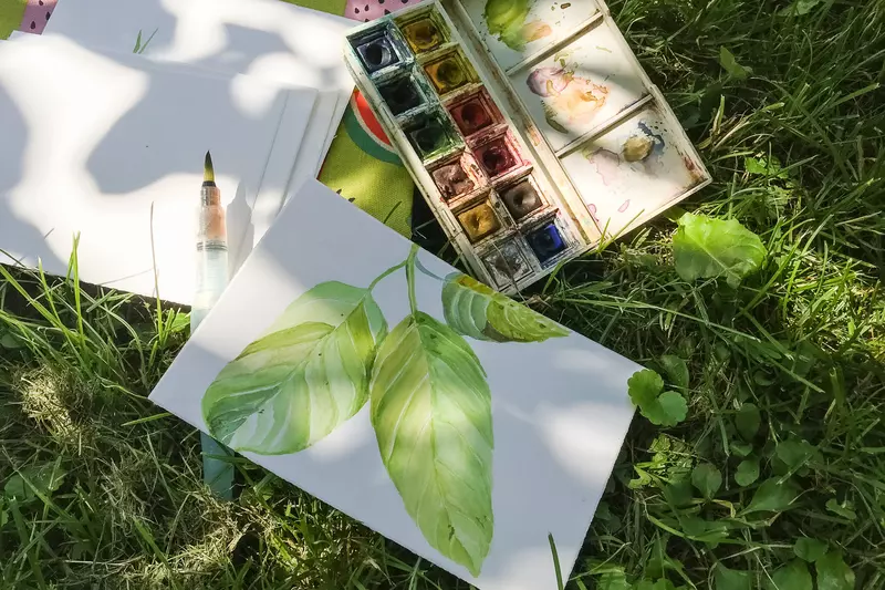 Selbstgemaltes Bild einer Pflanze mit Farben und Papier im Gras