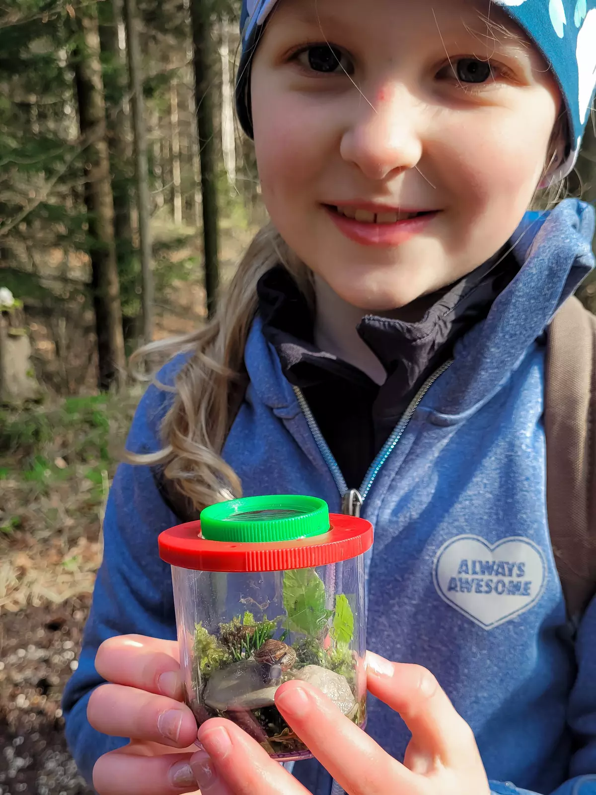 Mädchen mit befülltem Sammelglas mit Moos und Schnecke