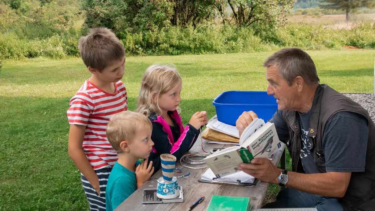 Guide zeigt Kindergruppe Vögel in einem Buch