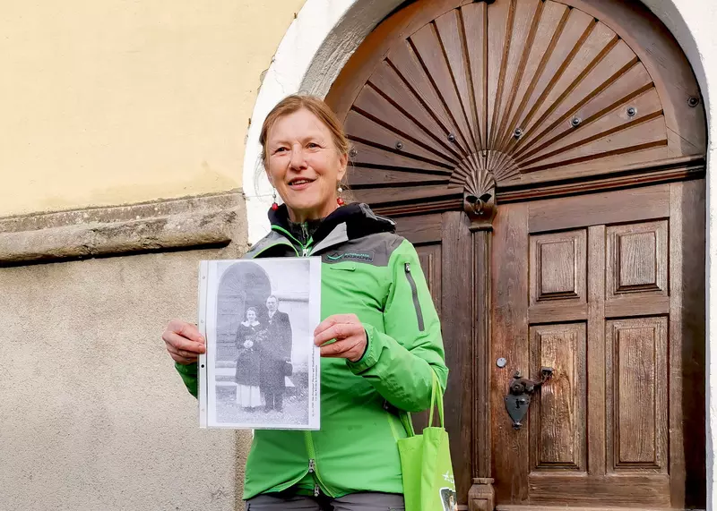 Rangerin steht für einer Holztür und hält ein schwarz-weiß-Bild in den Händen