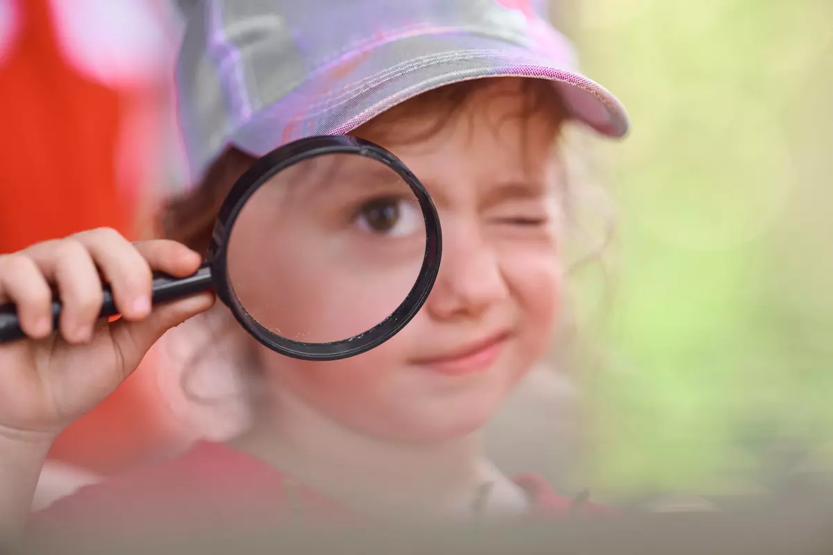 Kind schaut duch die Lupe