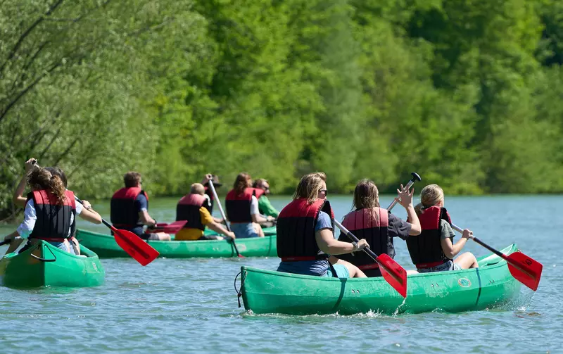 Menschen mit Schwimmweste in grünen Kanus 