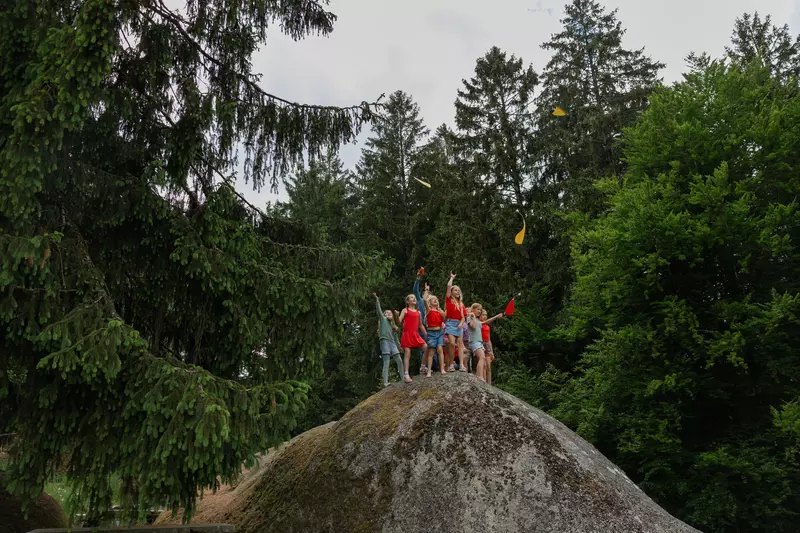 Kindergruppe mit Flugobjekten auf Stein 