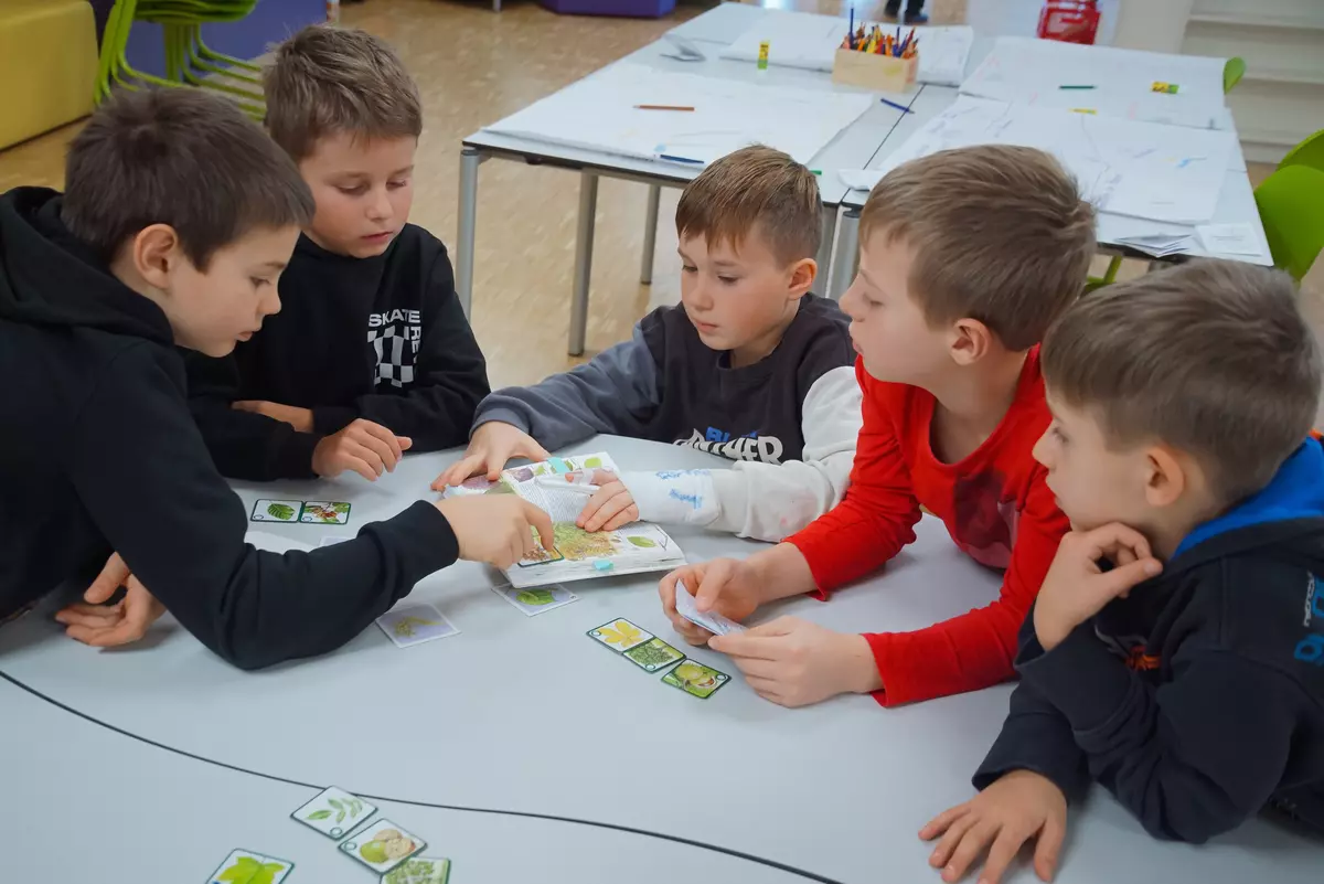 Fünf Burschen diskutieren bei einem Kartenspiel zum Thema Pflanzen
