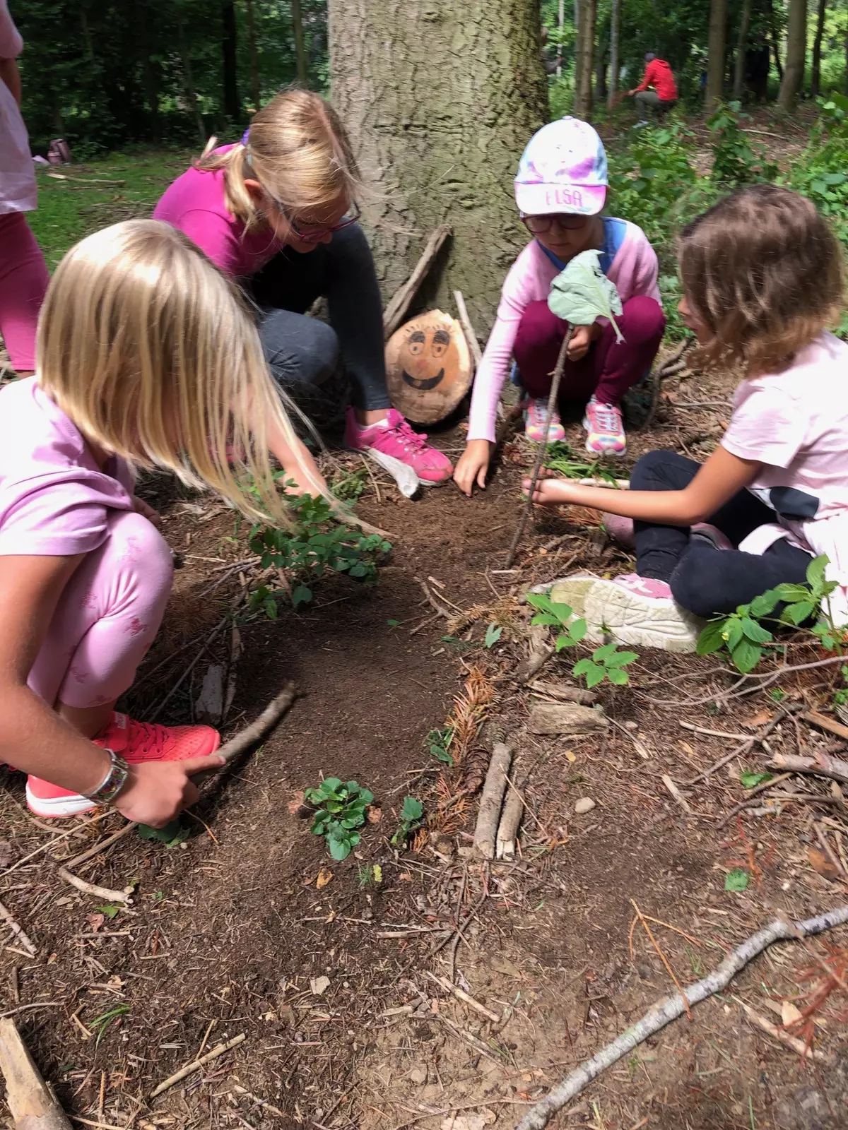Drei Kinder untersuchen den Waldboden