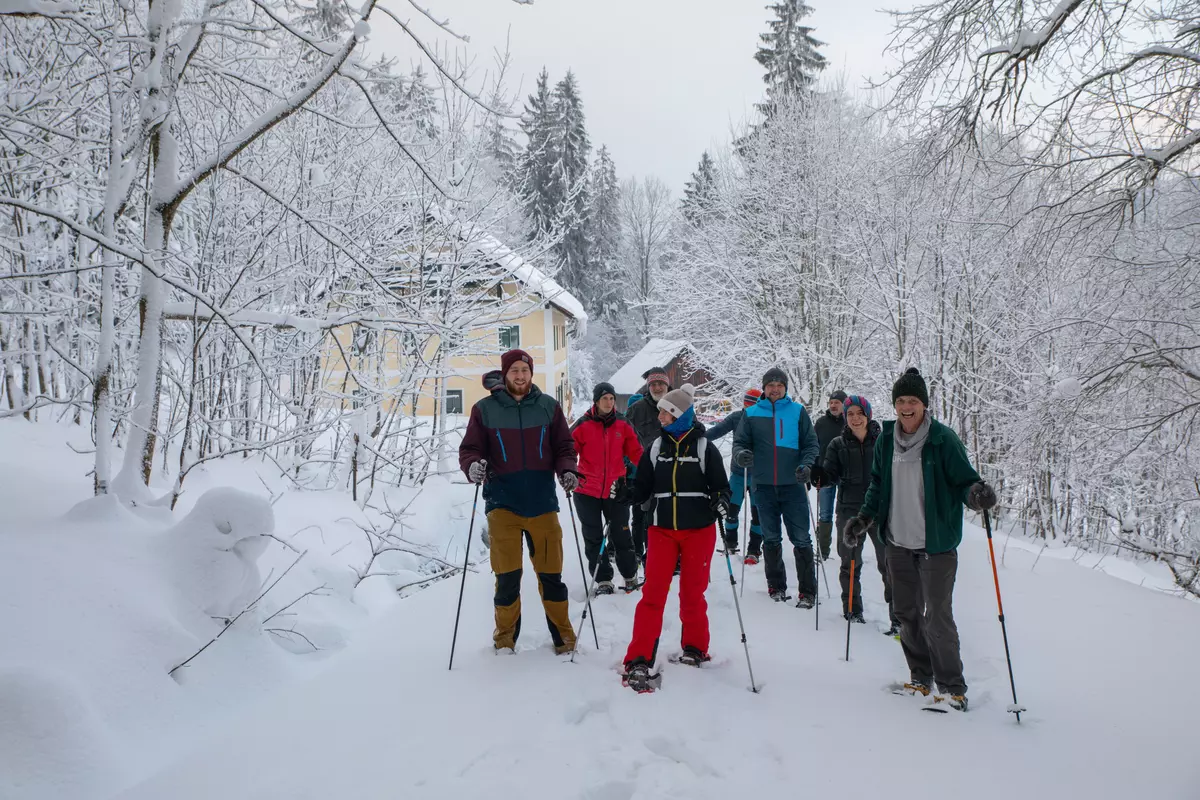 Schneeschuhgruppe im Winterwald vor Haus