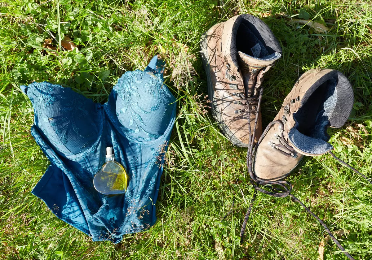 Ein Fläschchen Kräuterlikör und Wanderschuhe liegen in der Wiese
