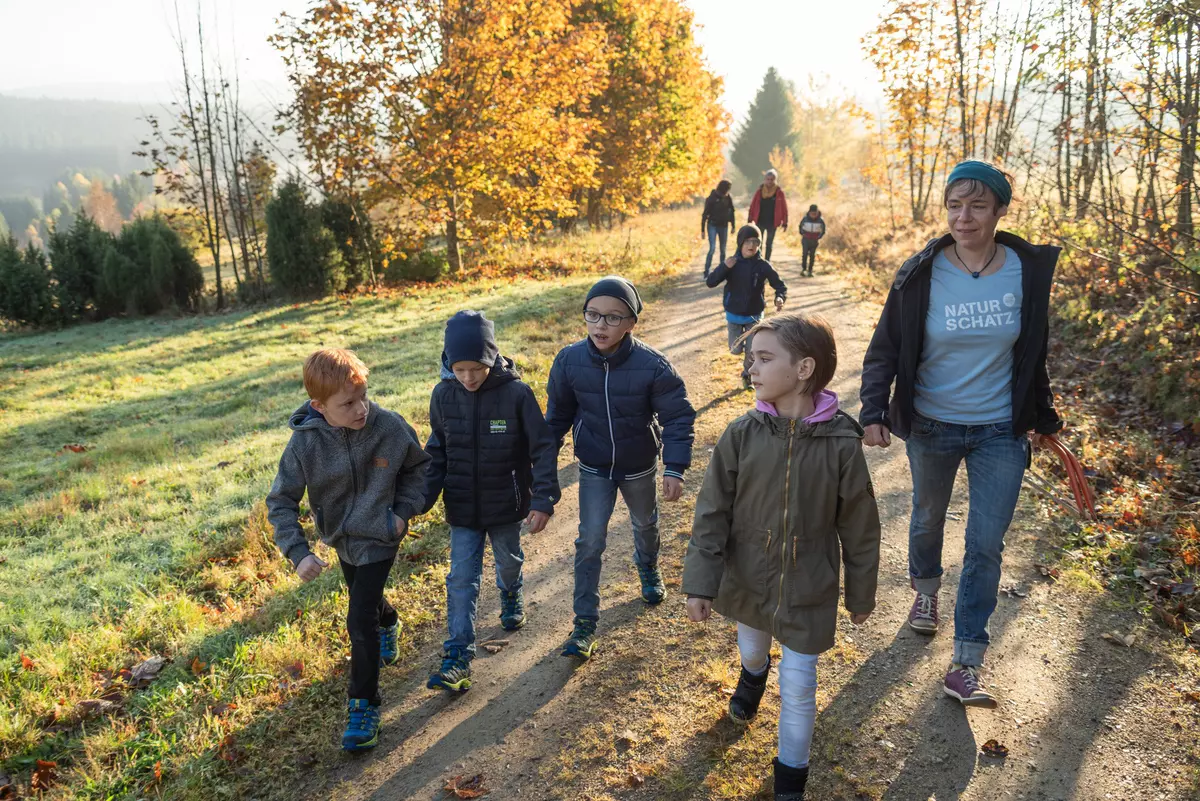 Weiblicher Guide mit Kindergruppe auf Forstweg im Herbst