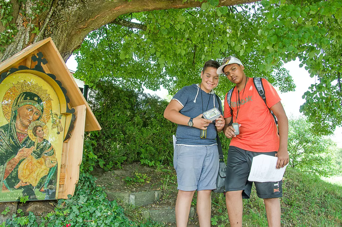 2 Burschen mit GPS unter Baum mit Heiligenbild