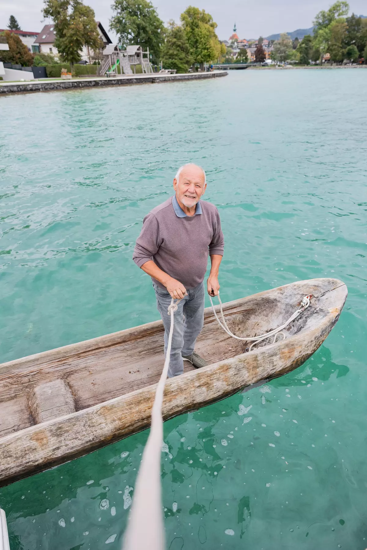 Mann mit Seil auf selbstgebautem Kanu im Wasser