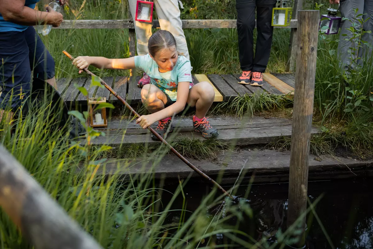 Mädchen mit Stock auf einem Steg im Moor