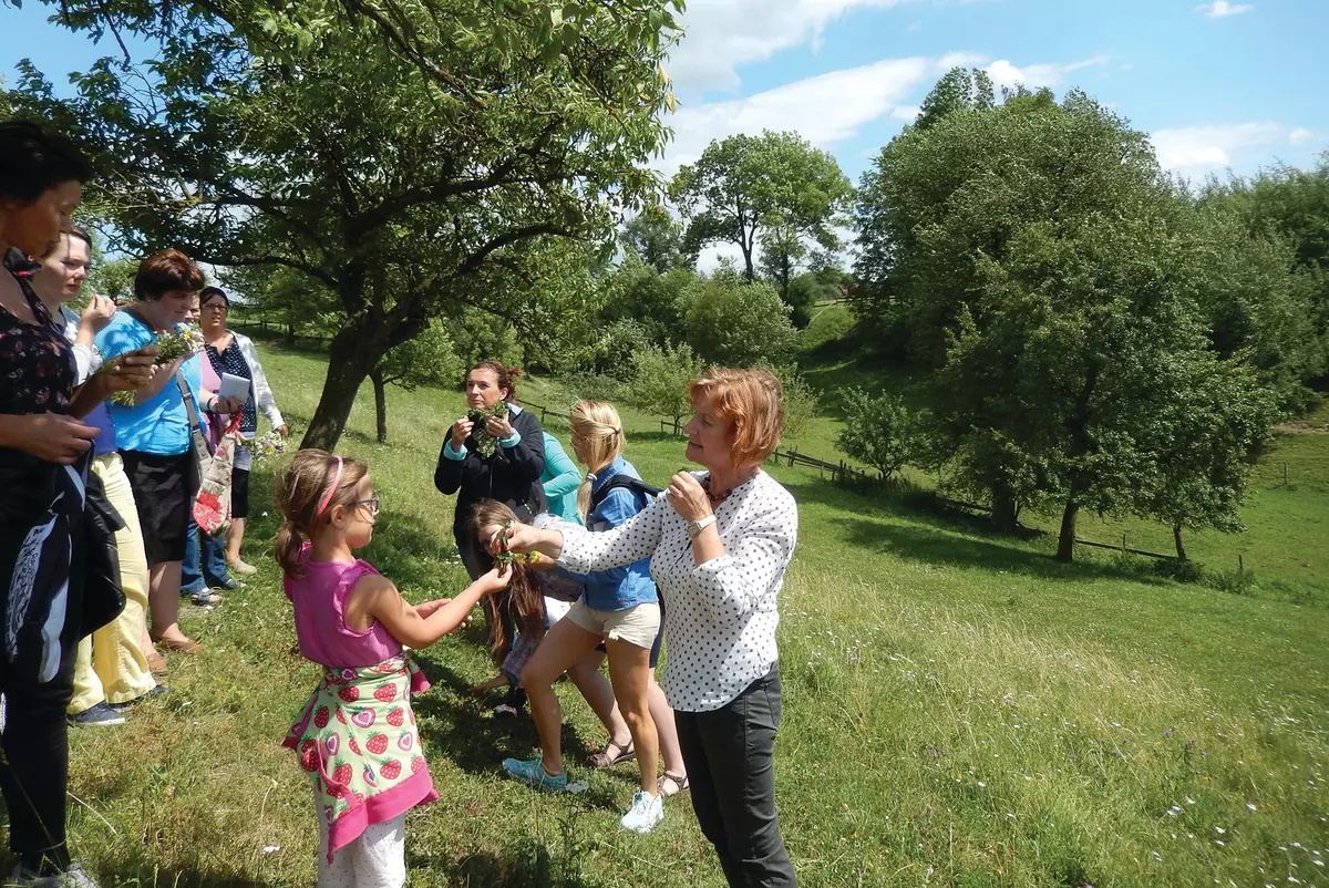 Mehrere Kinder und Erwachsene mit Blumen und Kräutern auf einer Wiese