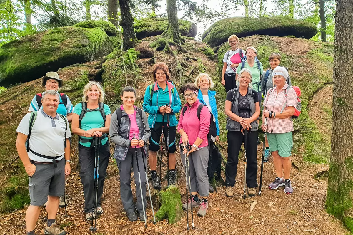 Gruppe stehend vor moosgrünen Findlingen
