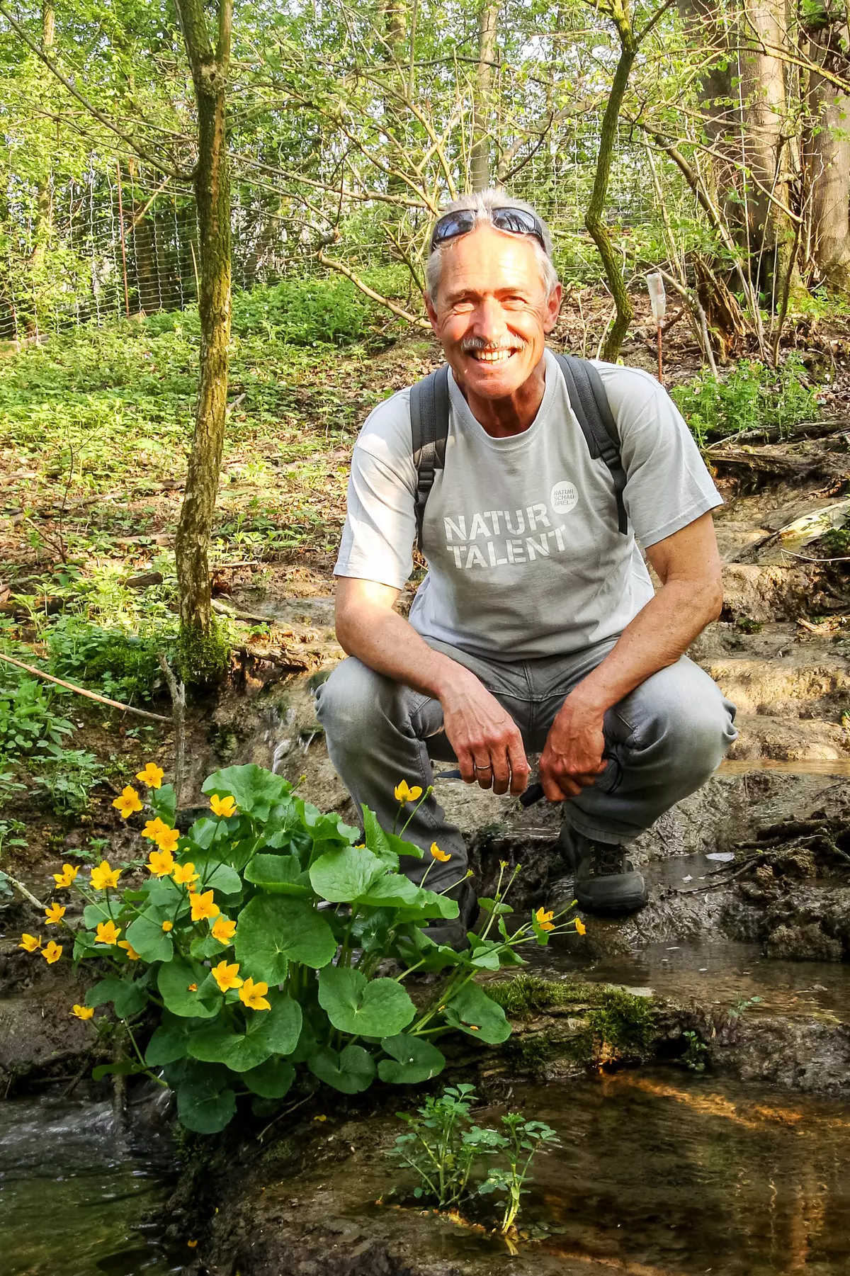 Guide hockend neben Sumpfdotterblumen