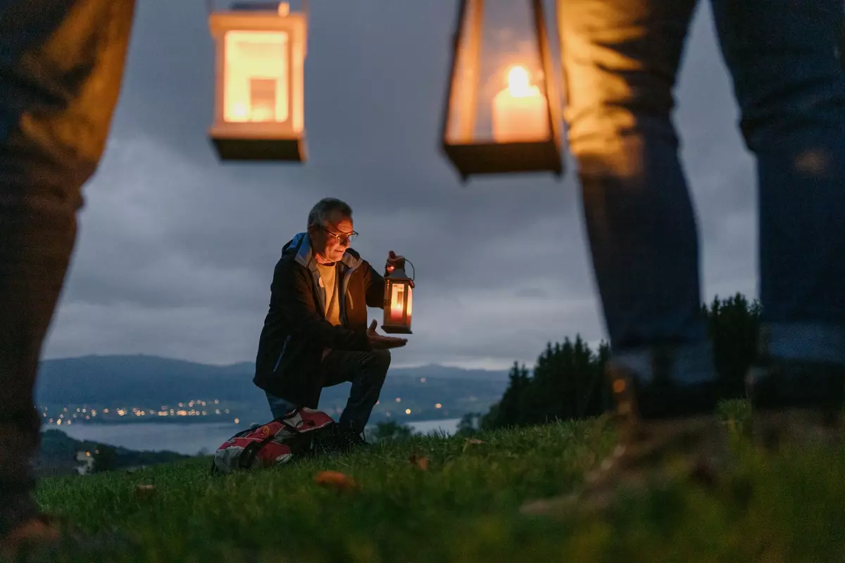 Gruppe steht auf Wiese mit Laternen in der Dämmerung