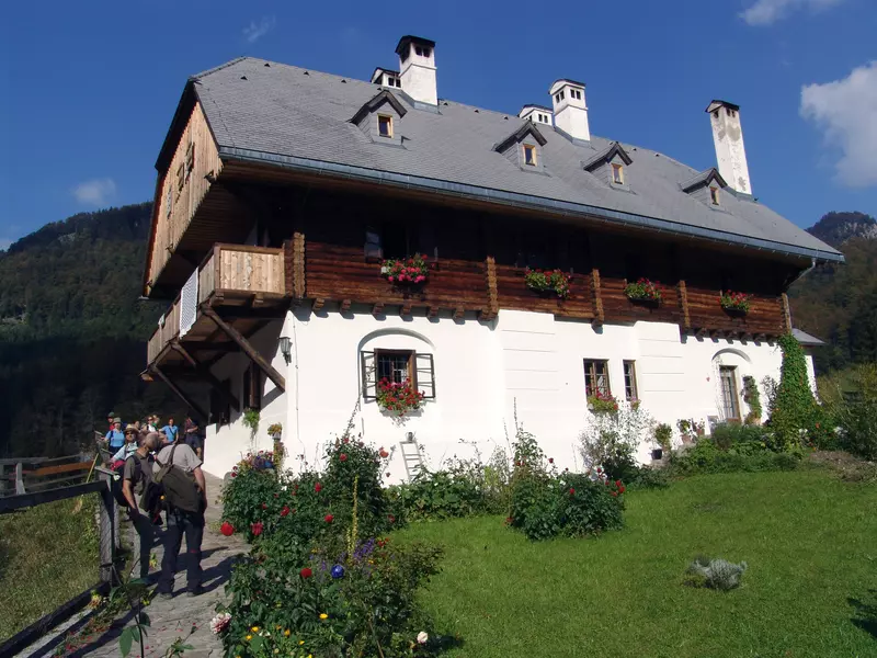 Haus mit Blumengarten und Menschen davor