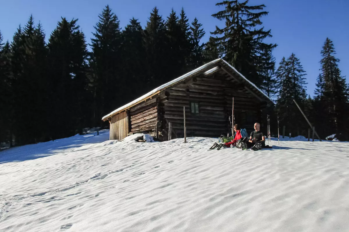 Gruppe vor verschneiter Almhütte 