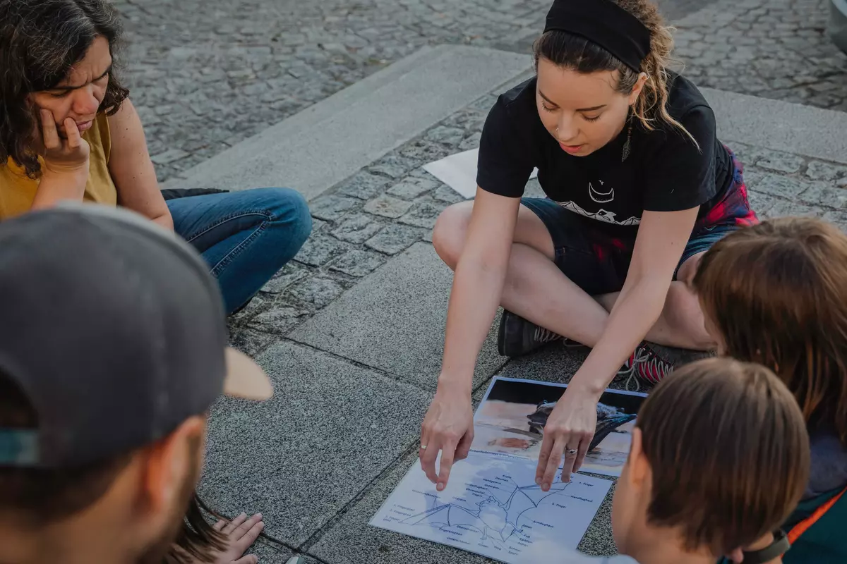 Guide erklärt einer teilnehmenden Familie etwas über Fledermäuse