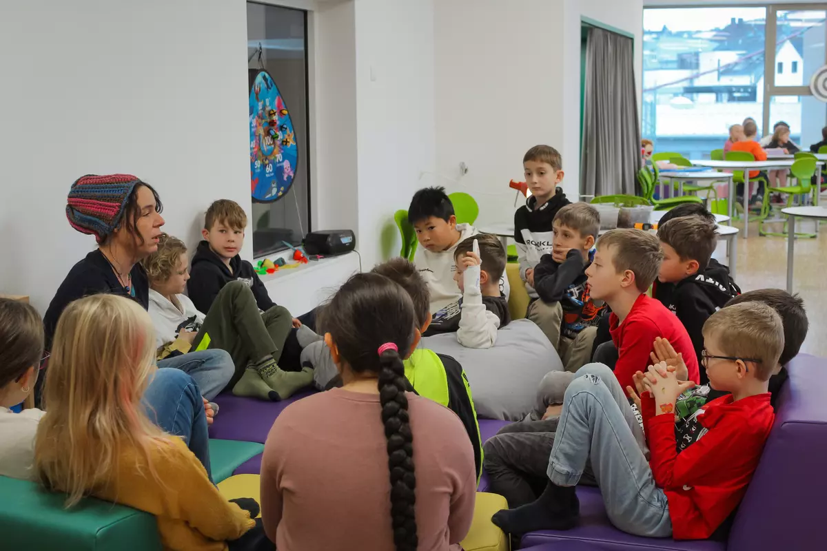 Einige Kinder sitzen mit einem Guide im Halbkreis
