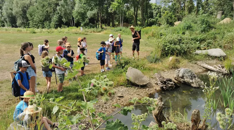 Guide mit einer Gruppe von Kindern an einem Gewässer