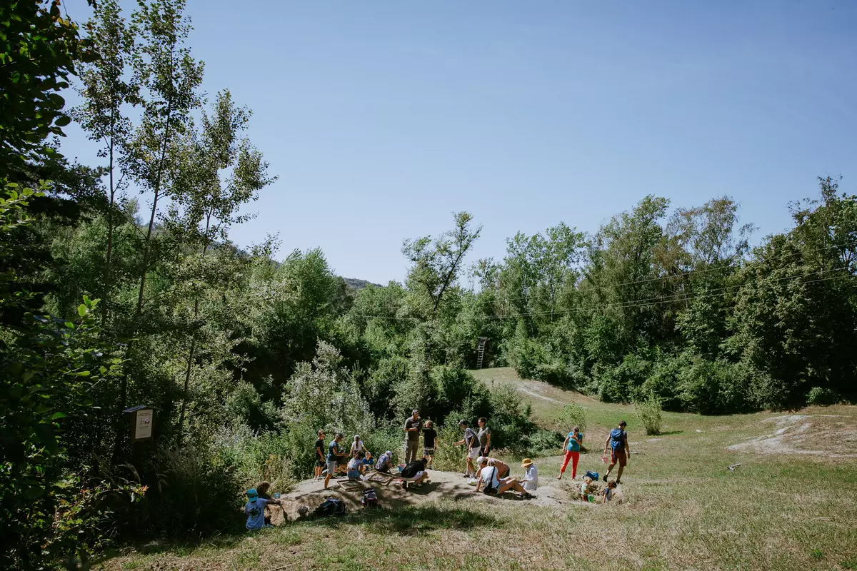 Gruppe von Teilnehmenden mit einigen Kindern auf einem bewaldeten Feld