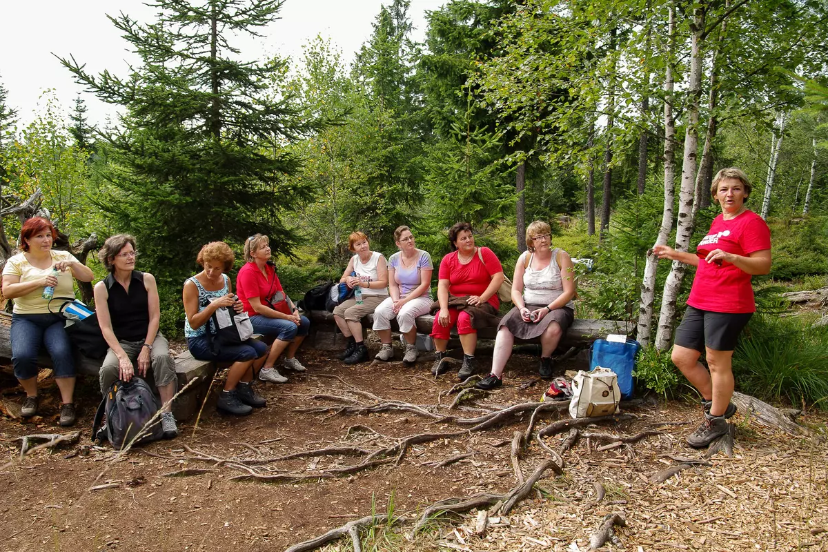 Frauengruppe sitzend auf Holzbänken mit weiblichem Guide