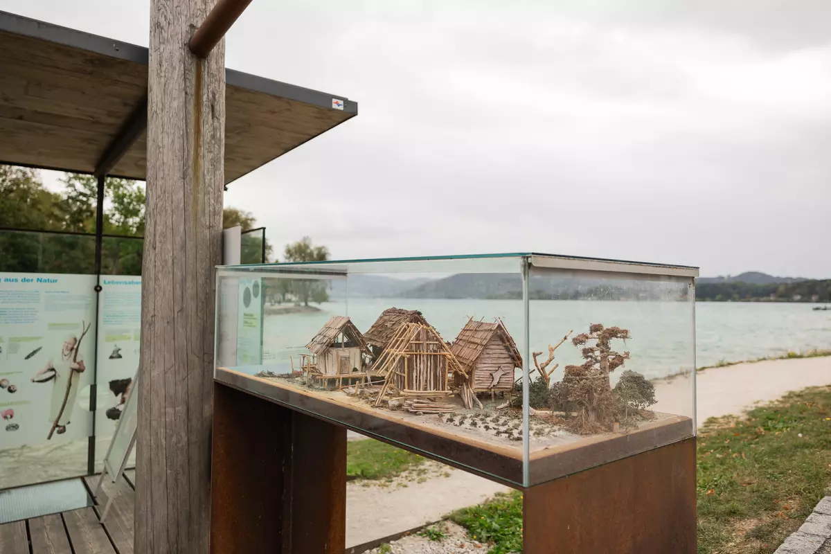 Miniaturpfahlbauten aus kleinen Holzstücken in einer Glasvitrine