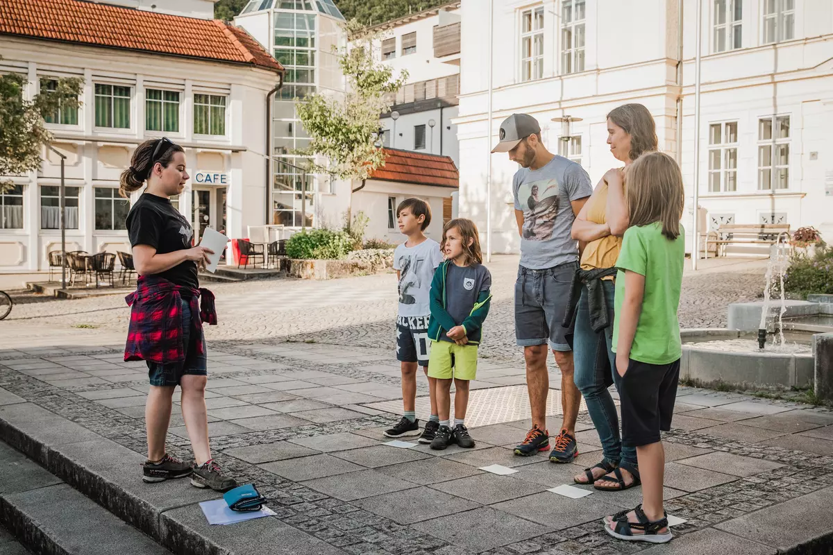 Guide spricht mit teilnehmender Familie auf einem Ortsplatz
