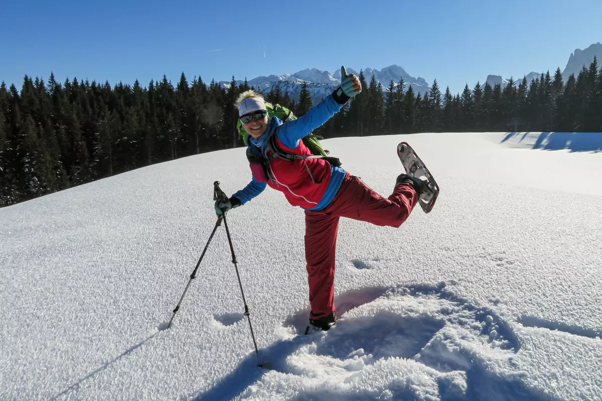 Weiblicher Guide stehend auf einem Bein mit Schneeschuhen