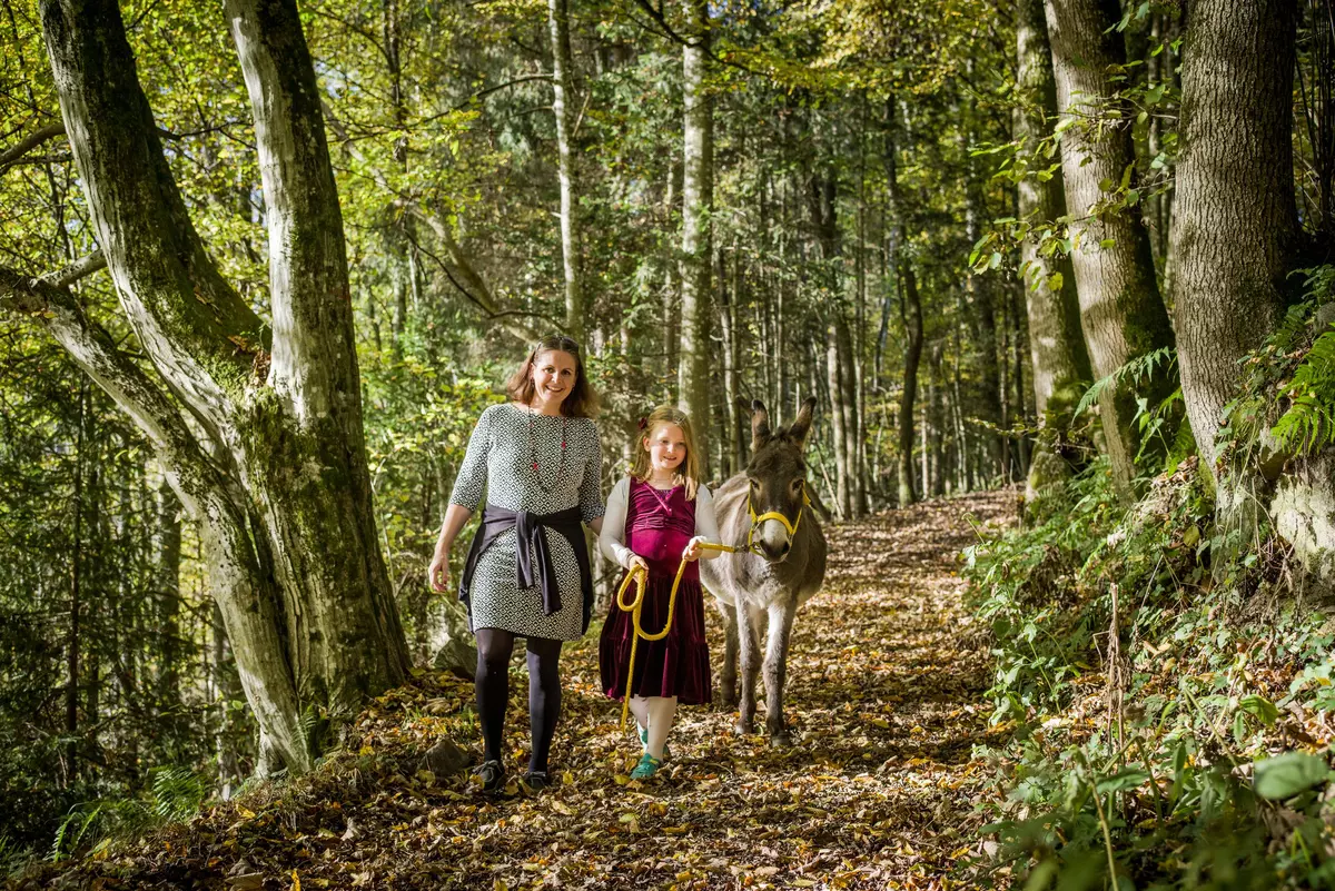 Mutter mit Kind und Esel am Seil im Wald