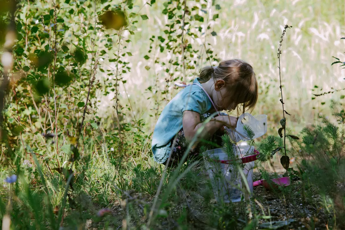 Mädchen untersucht den Erdboden in einem Feld zwischen hohen Pflanzen