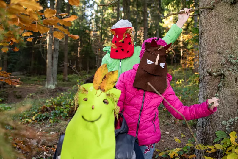 Kinder mit bunten Masken im Wald