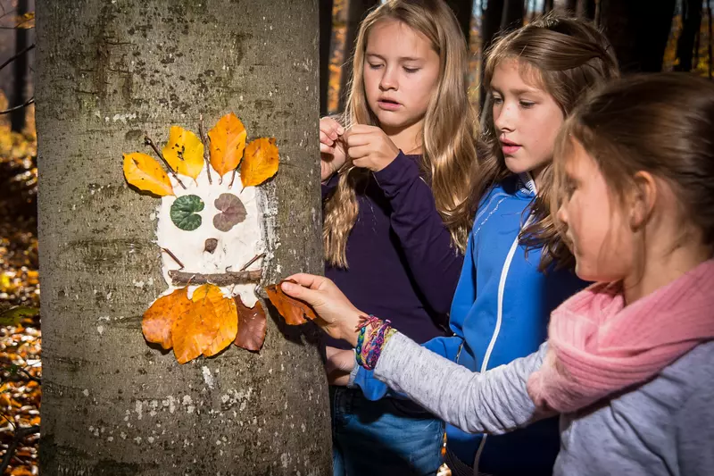 Mädchen schmücken Baumstamm mit Waldgesicht