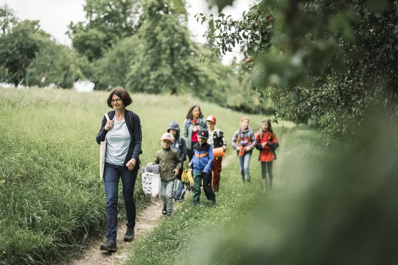 Guide mit einer Gruppe von Kindern auf einem Wanderweg neben dem Wald